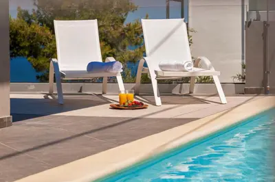 two chairs sitting next to a swimming pool at Blue Sea Chania Villa in Chania Town