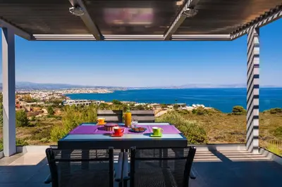 a table on a balcony with a view of the ocean at Blue Sea Chania Villa in Chania Town