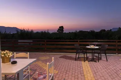 a patio with a table and chairs at sunset at Nikis Apartments Kisamos in Drapaniás