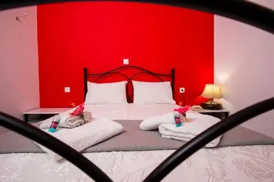 a bedroom with a red wall and a bed with towels at Nikis Apartments Kisamos in Drapaniás