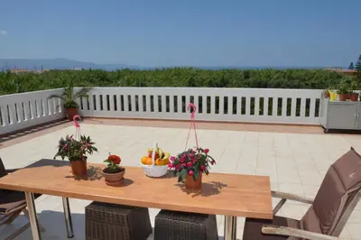 a wooden table with fruits and plants on a patio at Kostaspant apartment in Gerani Chanion