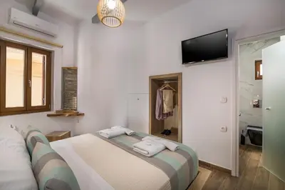 a bedroom with a bed and a tv on the wall at Evlimeni Suites in Chania Town