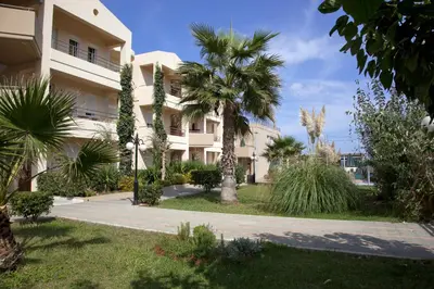 a building with palm trees in front of it at Maleme Mare in Maleme