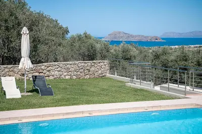 a pool with an umbrella and a chair and a table and an umbrella at Villa Athinais in Gerani Chanion