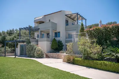 a large white house with bushes and trees at Villa Athinais in Gerani Chanion