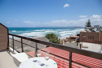 a balcony with a table and chairs and the ocean at Nefeli Rooms in Agia Marina Nea Kydonias
