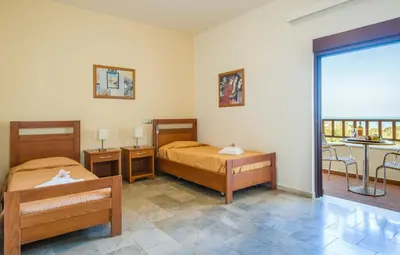 a bedroom with two beds and a balcony at ERIA RESORT for people with special abilities in Maleme