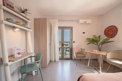 a hotel room with a table and chairs and a balcony at Sonio Beach - Que Bella Collection in Plataniás