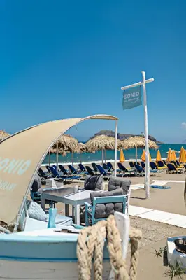 a beach with a table and chairs and umbrellas at Sonio Beach - Que Bella Collection in Plataniás