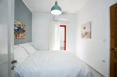 a white bedroom with a bed and a window at La Vita Moderna in Chania Town