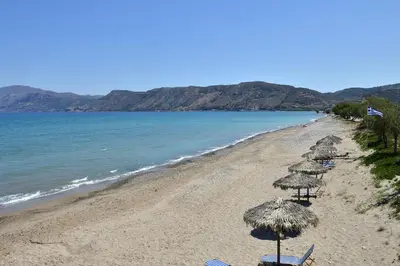 a beach with chairs and umbrellas and the ocean at Mousa Thalia in Kissamos
