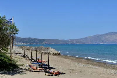 a beach with chairs and umbrellas and the ocean at Mousa Thalia in Kissamos