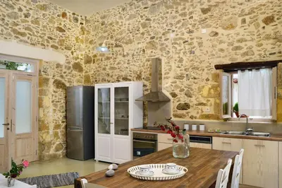 a kitchen with a wooden table and a stone wall at Mousa Thalia in Kissamos