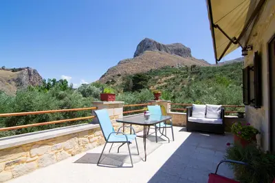 a patio with a table and chairs and mountains at Mansion Rokka in Kissamos
