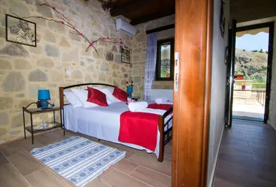 a bedroom with a white bed with red pillows at Mansion Rokka in Kissamos