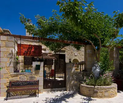 a bench in front of a building with a tree at Mansion Rokka in Kissamos