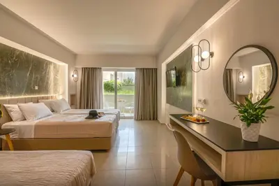 a hotel room with two beds and a desk with a mirror at Castro Beach Hotel in Maleme
