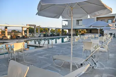 a patio with chairs and an umbrella next to a pool at Castro Beach Hotel in Maleme