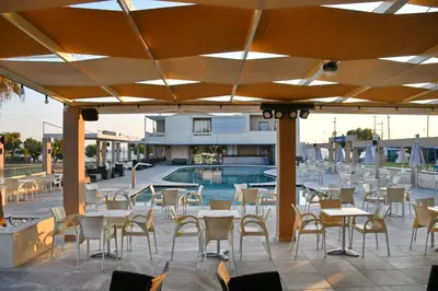 a patio with tables and chairs and a swimming pool at Castro Beach Hotel in Maleme