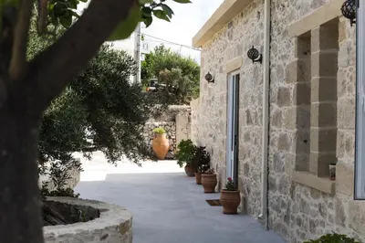 a stone alley with potted plants on the side of a building at Margarita's Stone House in Plátanos
