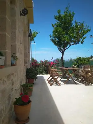 a patio with potted plants and a table and a tree at Margarita's Stone House in Plátanos