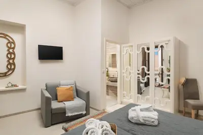 a room with a bed and a chair and a mirror at Elia Palazzo Hotel in Chania Town