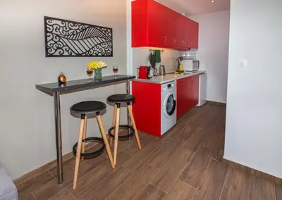 a kitchen with red cabinets and two stools at Olive Garden Holiday Home steps to Beach 1 in Kato Daratso