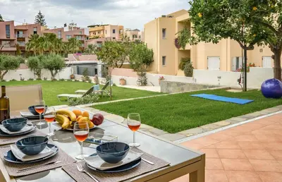 a table with food and wine on a patio with a yard at Olive Garden Holiday Home steps to Beach 1 in Kato Daratso