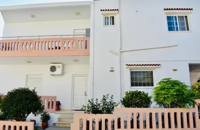 a white house with a pink fence in front of it at Cozy Renovated Apartment 