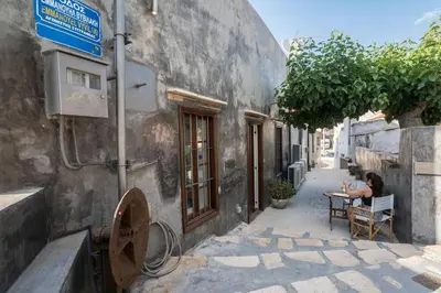 a woman sitting at a table outside of a building at kito- transformed house on the water's edge in Chania Town