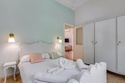 a white bedroom with a white bed and a mirror at Samouil Apartment steps from the beach in Chania Town