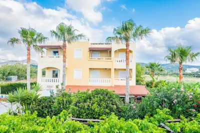 a building with palm trees in front of it at Thalassa Apartments in Kissamos