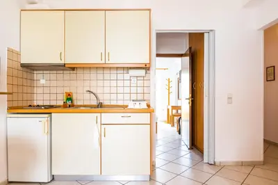 a kitchen with white cabinets and a tile floor at Thalassa Apartments in Kissamos