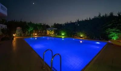 a large blue swimming pool at night with lights at Golden Rose Suites in Kolymvari