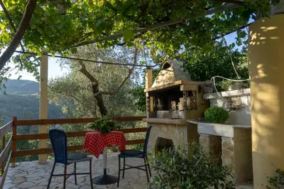 a patio with two chairs and a table and a fireplace at Cottage home at South Chania in Grigorianá