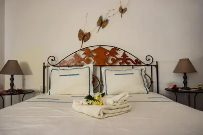 a bed with a white blanket and butterflies on the wall at Cottage home at South Chania in Grigorianá
