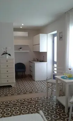 a kitchen with white cabinets and a table and a chair at White Rose in Chania Town
