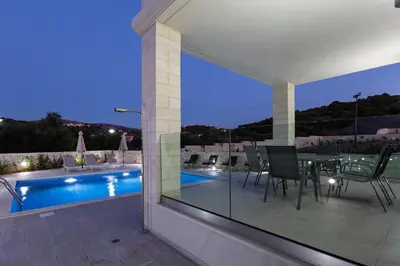 a patio with a table and chairs next to a swimming pool at Eudora Luxury Stone Villa in Almirida