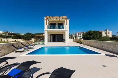 a swimming pool with chairs and a house at Eudora Luxury Stone Villa in Almirida