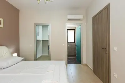 a bedroom with a white bed and a bathroom at Eudora Luxury Stone Villa in Almirida