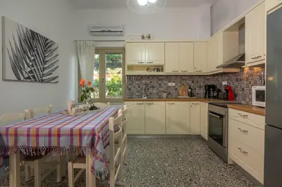 a kitchen with white cabinets and a table with a table cloth at Harmony House in Kissamos