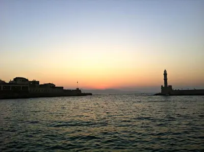 a lighthouse in the middle of the water at sunset at Cozy one-bedroom apartment in Halepa, Chania in Chania Town