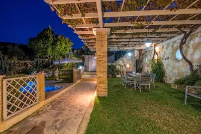 a patio with a table and chairs under a pergola at Niko's art Villa in Chania in Perivólia