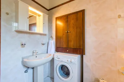 a bathroom with a washing machine and a sink at Femina in Pírgos Psilonérou