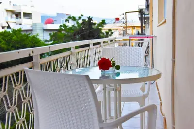 a table and chairs on a balcony with a flower on it at Steps From The Beach Aprt in Chania Town