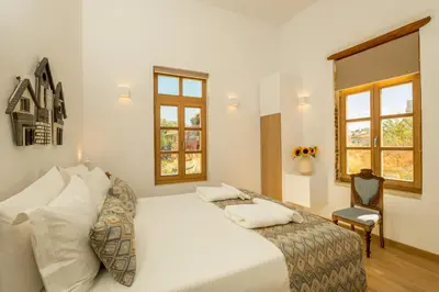 a bedroom with a bed and a chair and windows at Aelios Design Hotel in Chania Town