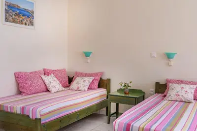 two beds in a room with pink and purple pillows at Armonia Apartments in Almirida