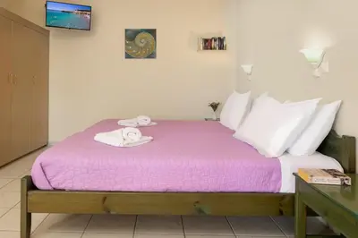 a bedroom with a bed with purple sheets and towels at Armonia Apartments in Almirida