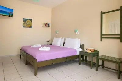 a bedroom with a bed with purple sheets and a mirror at Armonia Apartments in Almirida