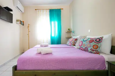 a bedroom with two beds with pink sheets at Armonia Apartments in Almirida